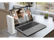 Charger l'image dans la galerie, Ordinateur portable ouvert sur un bureau, appel vidéo avec trois participants. Un haut-parleur blanc est à gauche.