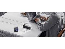 Charger l'image dans la galerie, Une personne travaille sur un ordinateur portable connecté à une batterie externe et à un téléphone. Une tasse de café est sur la table.