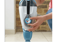 Charger l'image dans la galerie, La main d'une personne ajustant un cadran sur un balai vapeur bleu et blanc. Le cadran est mis au point.