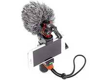 Charger l'image dans la galerie, Un microphone avec un pare-brise flou fixé à un support de téléphone avec un téléphone et une sangle.