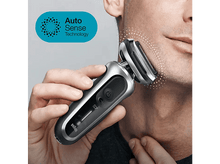 Charger l'image dans la galerie, Un homme se rase le visage avec un rasoir électrique argenté et noir.