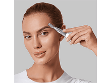 Charger l'image dans la galerie, Une femme utilisant une tondeuse à sourcils. Elle tient la tondeuse sur son sourcil, regardant la caméra.