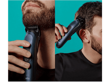 Charger l'image dans la galerie, Un homme se rase la barbe avec une tondeuse bleue et noire.