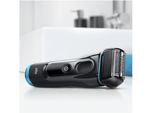 Charger l'image dans la galerie, Un rasoir Braun Series 5 noir et bleu sur une surface blanche, près d'un lavabo blanc.