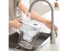 Charger l'image dans la galerie, Une personne remplissant une carafe filtrante blanche sous un robinet chromé dans une cuisine.