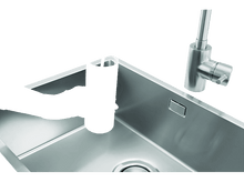 Charger l'image dans la galerie, Une main tient un verre sous un filtre à eau. L'eau coule dans le verre, le remplissant dans un évier en acier inoxydable. Le fond est blanc.