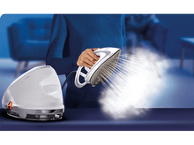 Charger l'image dans la galerie, Une femme repassant avec de la vapeur d'un fer blanc, à côté d'un générateur de vapeur blanc.