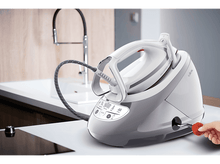 Charger l'image dans la galerie, Station de repassage avec fer à repasser sur une surface blanche. Une main insère une prise rouge. Le mot 'Calor' est visible.