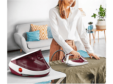 Charger l'image dans la galerie, Femme repassant une chemise sur une planche avec un fer à repasser générateur de vapeur, blanc et rouge.