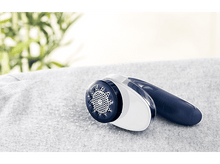 Charger l'image dans la galerie, Un rasoir à tissu sur une surface grise, avec des feuilles floues en arrière-plan.