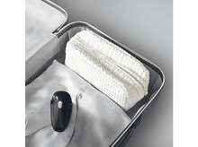 Charger l'image dans la galerie, Valise ouverte avec une chemise blanche pliée, un sac blanc à motifs gaufrés et un appareil vert foncé.