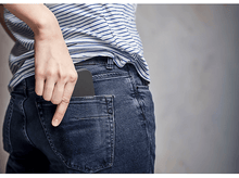 Charger l'image dans la galerie, Main d'une personne mettant un téléphone dans une poche de jean.