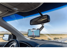 Charger l'image dans la galerie, Intérieur de voiture avec téléphone sur support affichant la navigation, rétroviseur et vue de la route à travers le pare-brise.