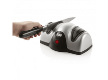 Charger l'image dans la galerie, Une personne utilise un aiguiseur de couteaux, avec un design argenté et noir, sur une surface blanche.