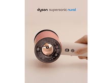 Charger l'image dans la galerie, Un sèche-cheveux Dyson Supersonic Nural rose et blanc est tenu par une main. Les composants internes sont visibles. Le fond est clair.