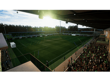 Charger l'image dans la galerie, Stade de foot avec terrain vert, gradins remplis et ciel clair.