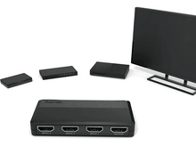 Charger l'image dans la galerie, Commutateur HDMI noir avec ports d'entrée et de sortie, avec d'autres appareils électroniques en arrière-plan.