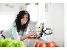Charger l'image dans la galerie, Femme touchant une tablette murale de cuisine. Tomates et laitue au premier plan.