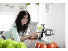 Charger l'image dans la galerie, Femme utilisant une tablette murale dans la cuisine, souriante.
