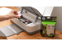 Charger l'image dans la galerie, Personne insérant une cartouche d'encre rose dans une imprimante HP. Une autre boîte d'encre est à droite.