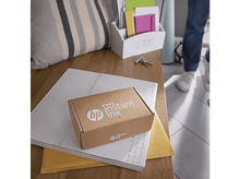 Charger l'image dans la galerie, Boîte en carton avec 'HP Instant Ink' imprimé, sur une table avec des enveloppes et des clés.