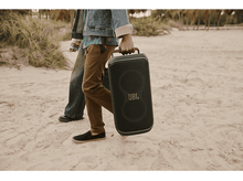 Charger l'image dans la galerie, Deux personnes marchant sur une plage, l'une portant une enceinte JBL noire avec le logo JBL.