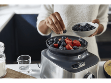 Charger l'image dans la galerie, Une personne ajoute des myrtilles à un bol de fraises. Un robot culinaire se trouve en dessous.