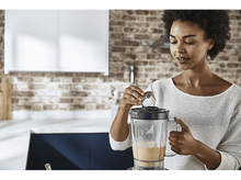 Charger l'image dans la galerie, Femme ajoutant des ingrédients dans un blender.