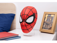 Charger l'image dans la galerie, Un masque de Spiderman sur un support, à côté de livres et d'un cadre photo.