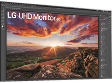 Charger l'image dans la galerie, Moniteur LG UHD 4K, pied argenté, écran montrant un coucher de soleil, bureau.
