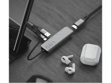 Charger l'image dans la galerie, Un bureau avec un ordinateur portable, un hub USB, des écouteurs et un étui de chargement. Fond sombre.