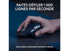 Charger l'image dans la galerie, La main d'une personne est sur une souris noire, sur une surface en bois.