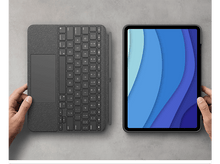 Charger l'image dans la galerie, Mains tenant un clavier et un iPad avec un fond découpé en papier bleu.