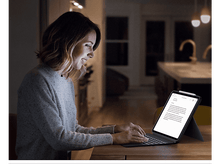 Charger l'image dans la galerie, Femme travaillant sur une tablette avec un clavier la nuit. La tablette est sur une table.