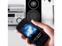 Charger l'image dans la galerie, Une main tenant un téléphone avec un écran de lecteur de musique, des haut-parleurs en arrière-plan.