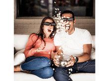 Charger l'image dans la galerie, Un couple portant des lunettes 3D, surpris par le pop-corn qui sort d'un bol.