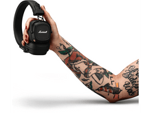 Charger l'image dans la galerie, Bras d'une personne tatouée tenant un casque Marshall noir. Fond blanc.