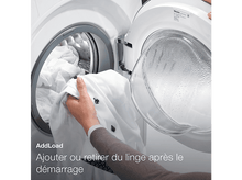 Charger l'image dans la galerie, Une main prend une chemise blanche dans une machine à laver ouverte.