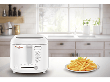 Charger l'image dans la galerie, Une friteuse blanche avec des frites dans une assiette, sur une table, dans une cuisine.