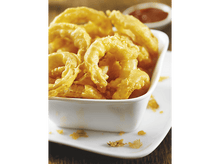 Charger l'image dans la galerie, Gros plan sur des oignons frits dans un bol blanc, avec une sauce rouge en arrière-plan.