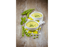 Charger l'image dans la galerie, Deux bols de soupe avec cuillères et gousses de petits pois sur table en bois.