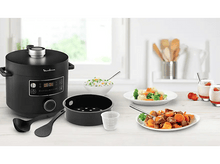 Charger l'image dans la galerie, Un multicuiseur Moulinex noir avec de la nourriture autour. Il y a un bol de riz, des légumes et de la viande.
