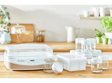 Charger l'image dans la galerie, Une scène de cuisine avec une yaourtière, des bocaux et des contenants, créant un cadre de préparation culinaire.