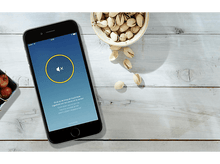 Charger l'image dans la galerie, Smartphone avec icône de silence et pistaches sur surface en bois.