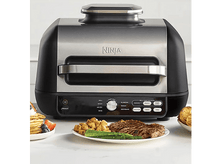 Charger l'image dans la galerie, Un grill Ninja noir et argenté avec de la nourriture cuite sur le comptoir.