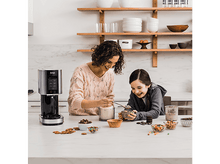 Charger l'image dans la galerie, Deux femmes et un enfant préparent de la glace. Divers ingrédients et machine sur un comptoir.