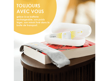 Charger l'image dans la galerie, Un appareil de soulagement de la douleur blanc, un étui et un livre, sur une table en bois marron.