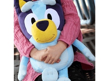 Charger l'image dans la galerie, Un enfant tenant une peluche Bluey. Le jouet est bleu, jaune et violet. Une chemise rose est portée.