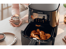 Charger l'image dans la galerie, Friteuse à air avec poulet frit et une main tenant un verre d'eau.