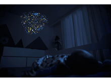 Charger l'image dans la galerie, Un enfant dort dans une pièce sombre. Un projecteur au plafond affiche des formes colorées.
